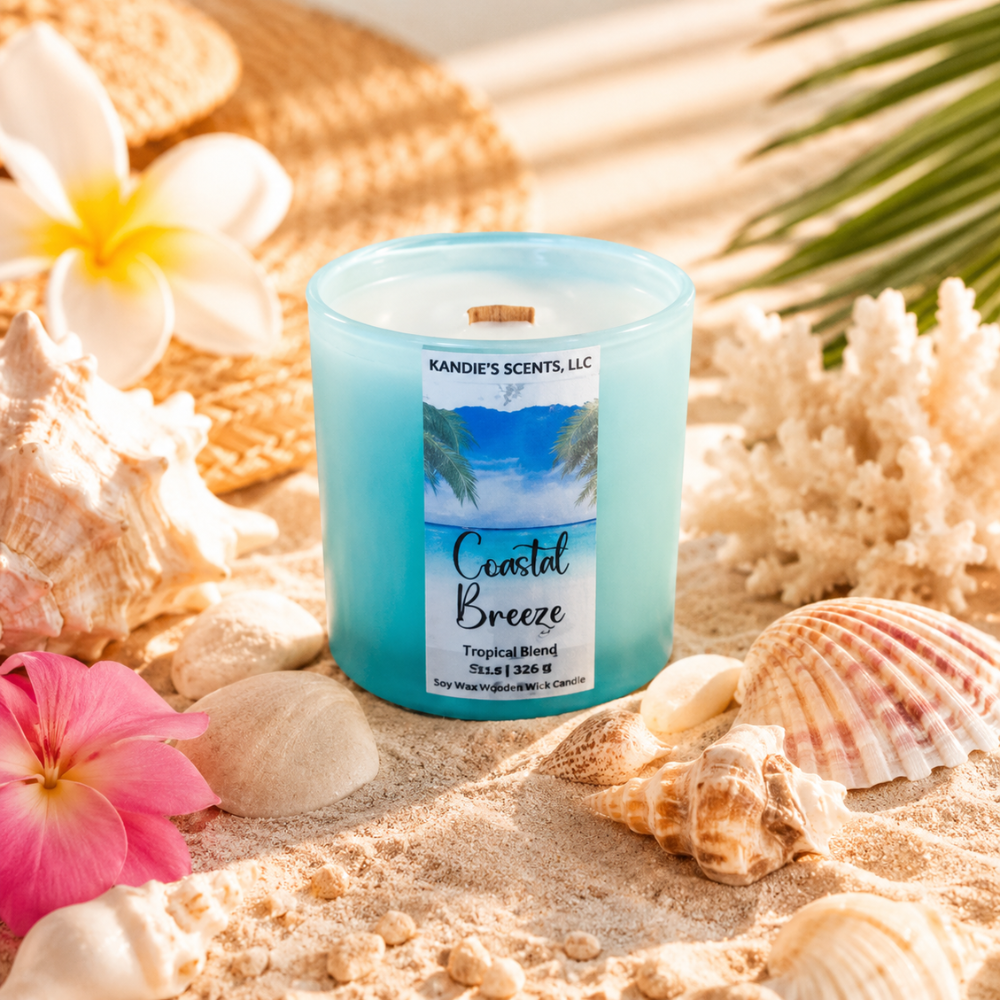 Candle labeled 'Coastal Breeze' surrounded by seashells, flowers, and sand with a palm leaf in the background.