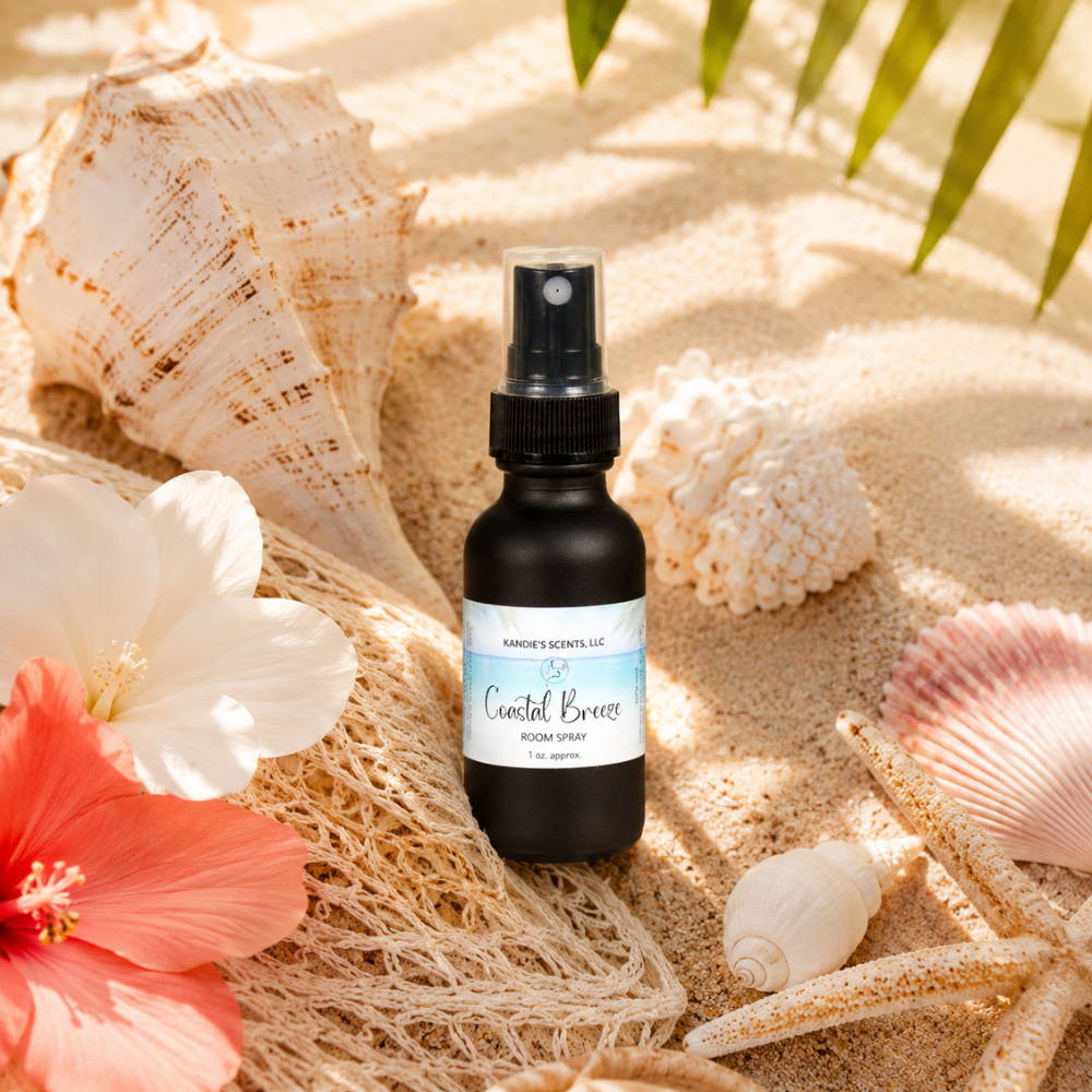 Room spray bottle labeled 'Coastal Breeze' on sand with seashells and flowers