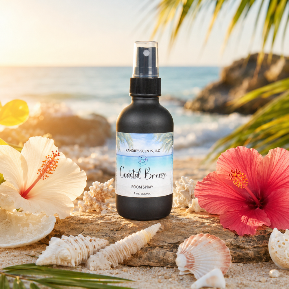 Room spray bottle labeled 'Coastal Breeze' on a beach setting with flowers and shells.