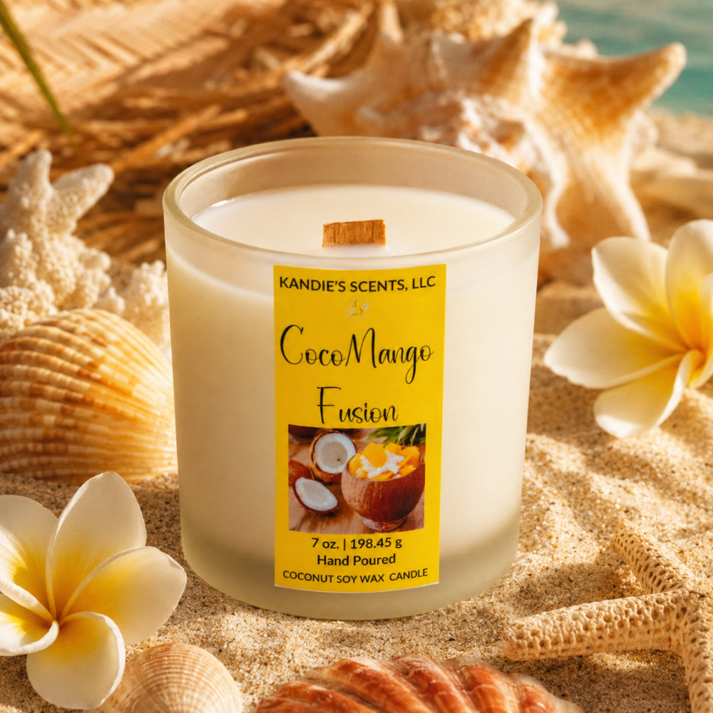 Candle labeled 'CocoMango Fusion' by Kandie's Scents on sand with flowers and shells.