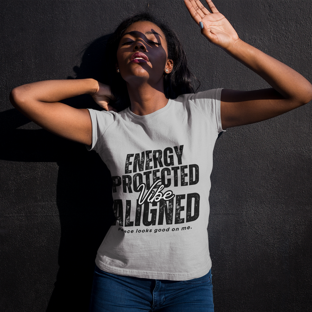 Woman wearing a t-shirt with text 'ENERGY PROTECTED Vibe ALIGNED' against a dark background