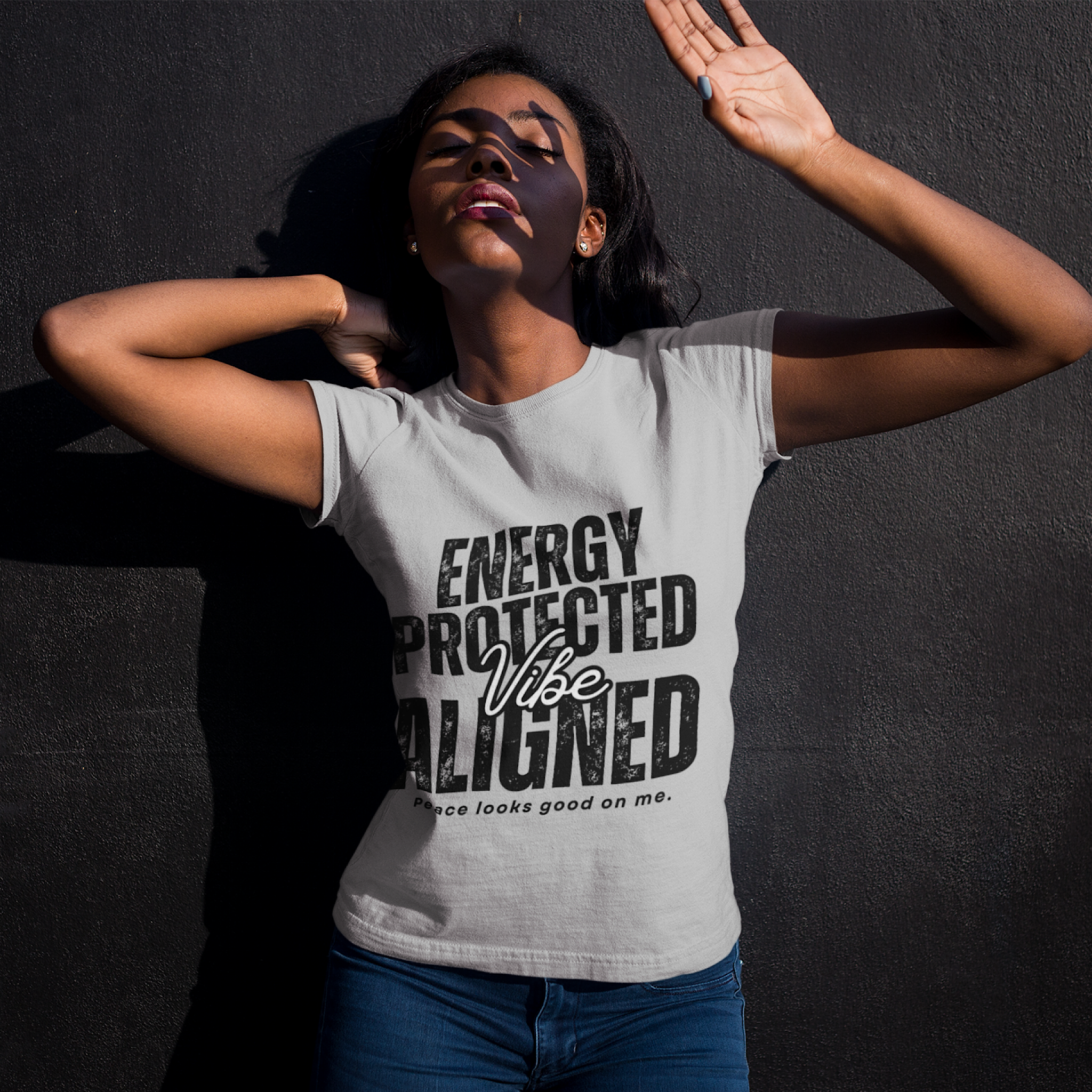 Woman wearing a t-shirt with text 'ENERGY PROTECTED Vibe ALIGNED' against a dark background