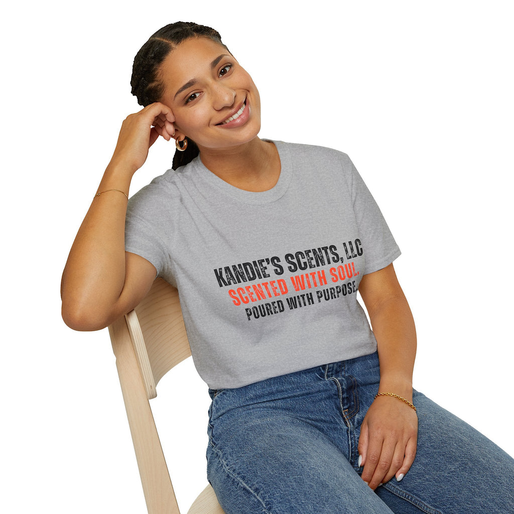 Woman wearing a gray t-shirt with 'Kandie's Scents, LLC - Scented with Soul. Poured with Purpose.' text, sitting on a chair against a white background