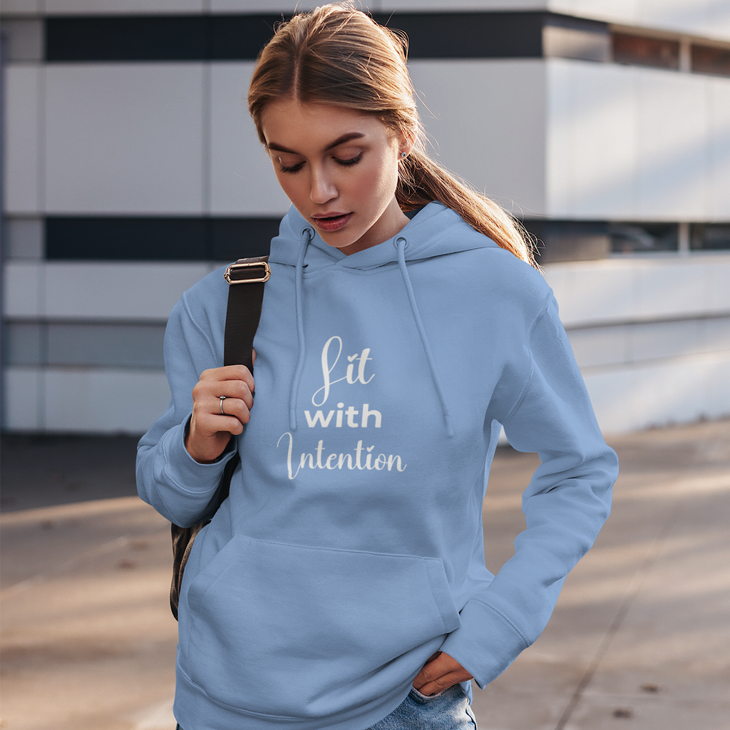 Woman wearing a light blue hoodie with 'Lit with Intention' text, standing outdoors.