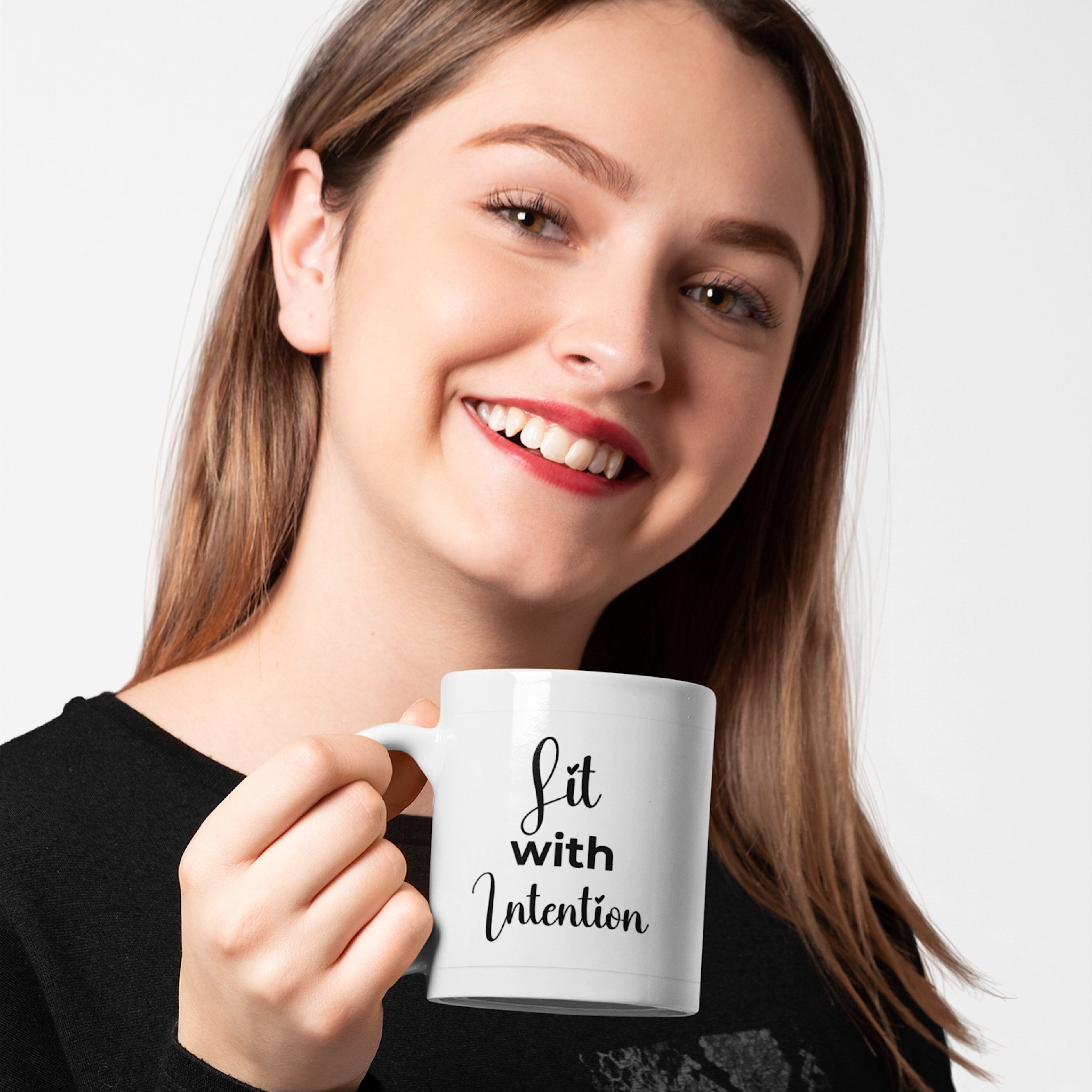 Woman holding a white mug with 'Lit with Intention' text on a plain background