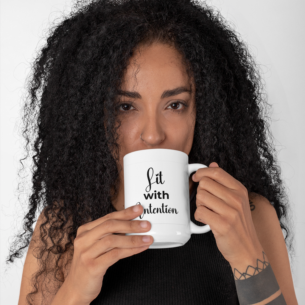 Woman holding a white mug with 'Lit with Intention' text against a plain background
