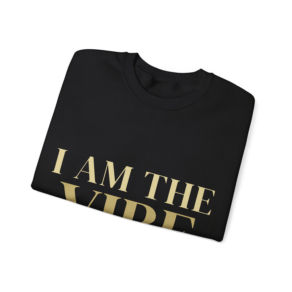 Folded black sweatshirt with 'I AM THE VIBE' text in gold on a white background
