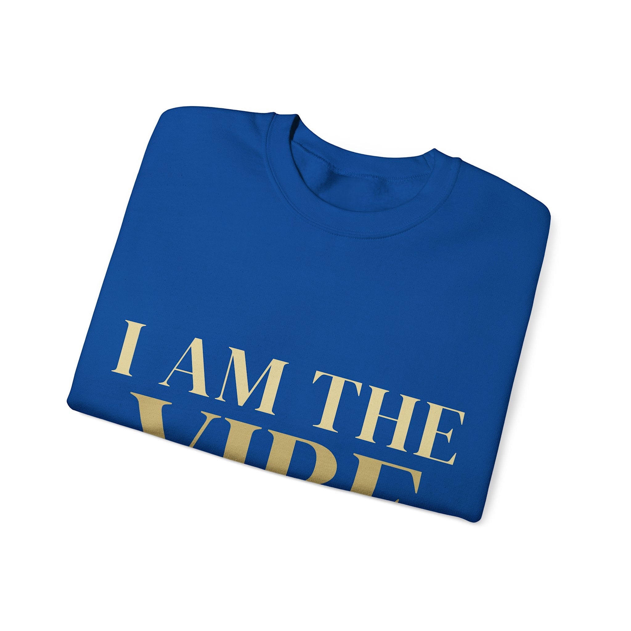 Folded blue t-shirt with 'I AM THE VIBE' text in gold on a white background