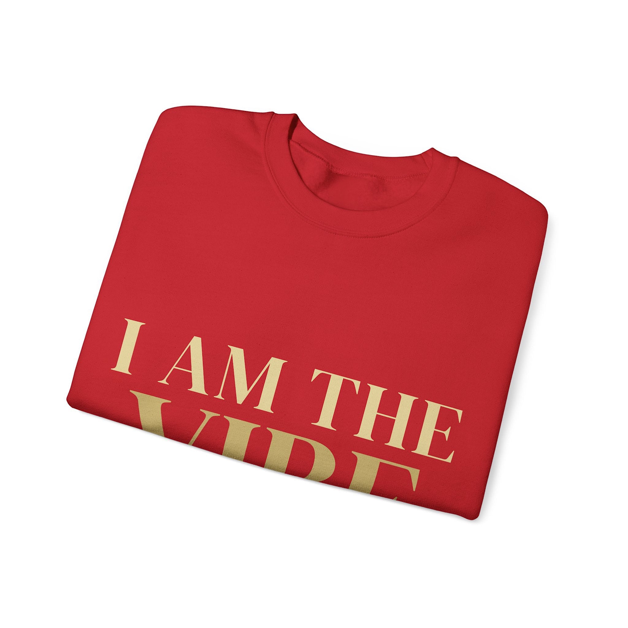 Folded red shirt with 'I AM THE VIBE' text in gold on a white background