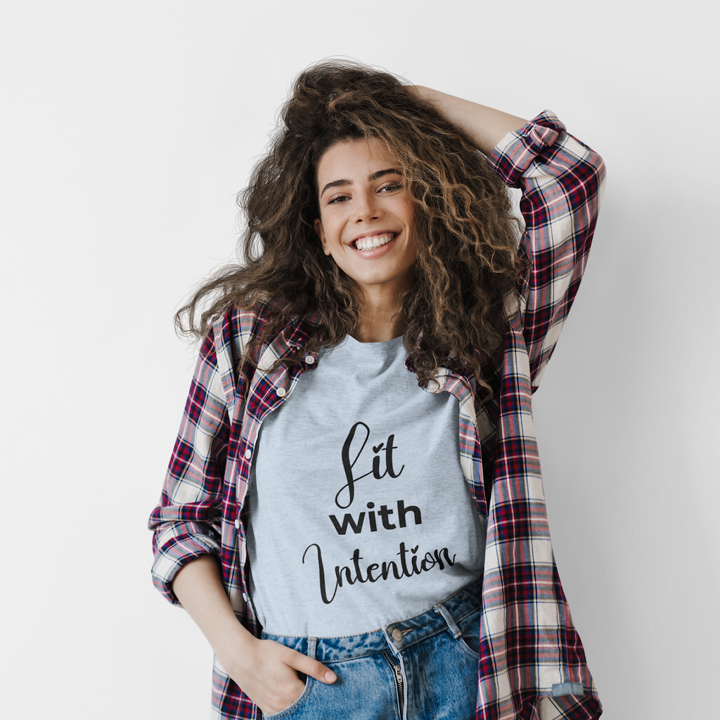 Woman wearing a plaid shirt over a t-shirt with 'Lit with Intention' text, smiling against a white background