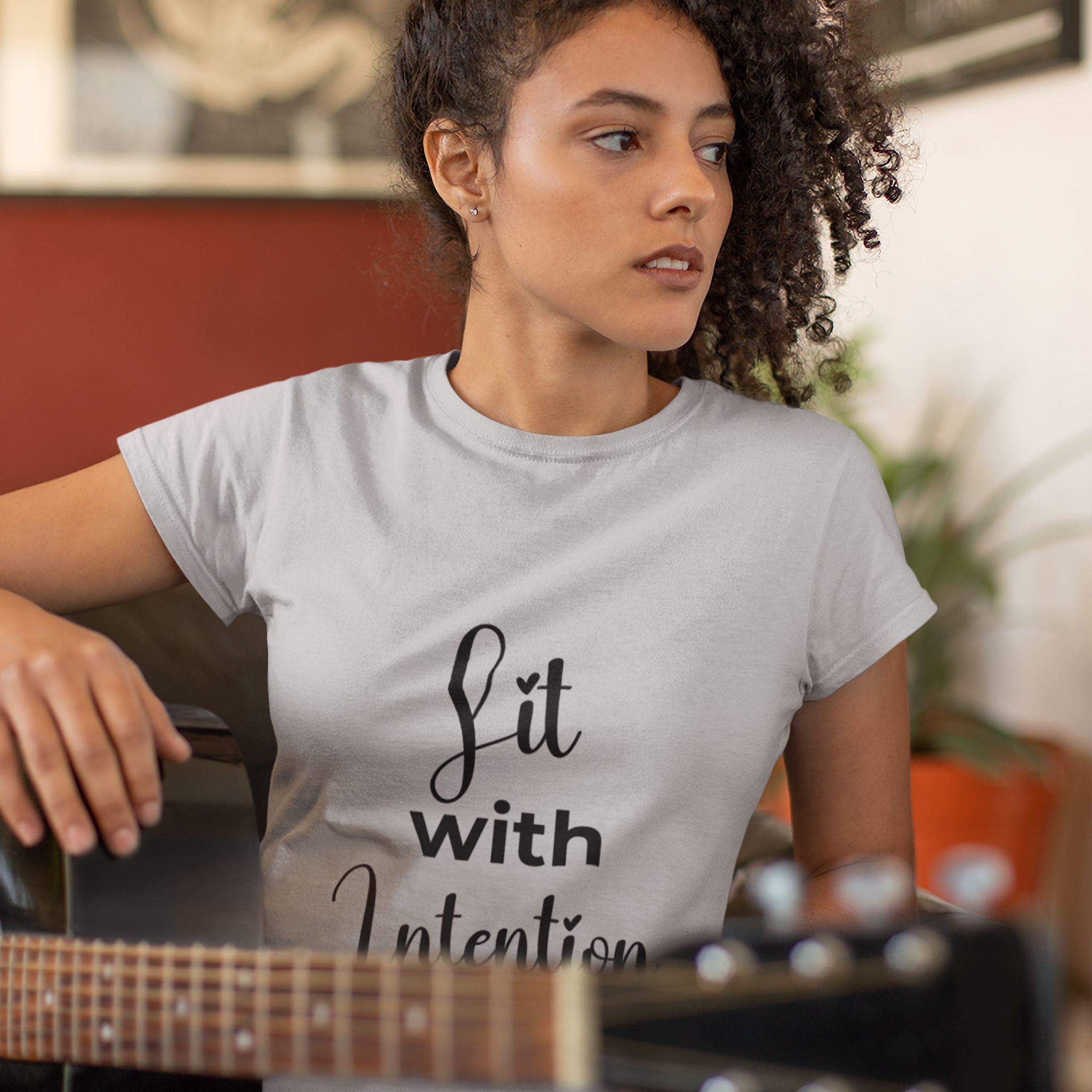 Woman wearing a t-shirt with 'Lit with Intention' text, holding a guitar.