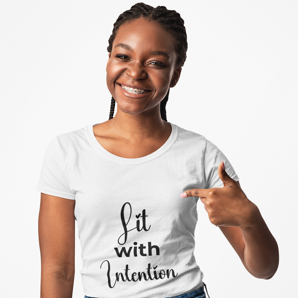Woman wearing a white t-shirt with 'Lit with Intention' text, pointing to the text.