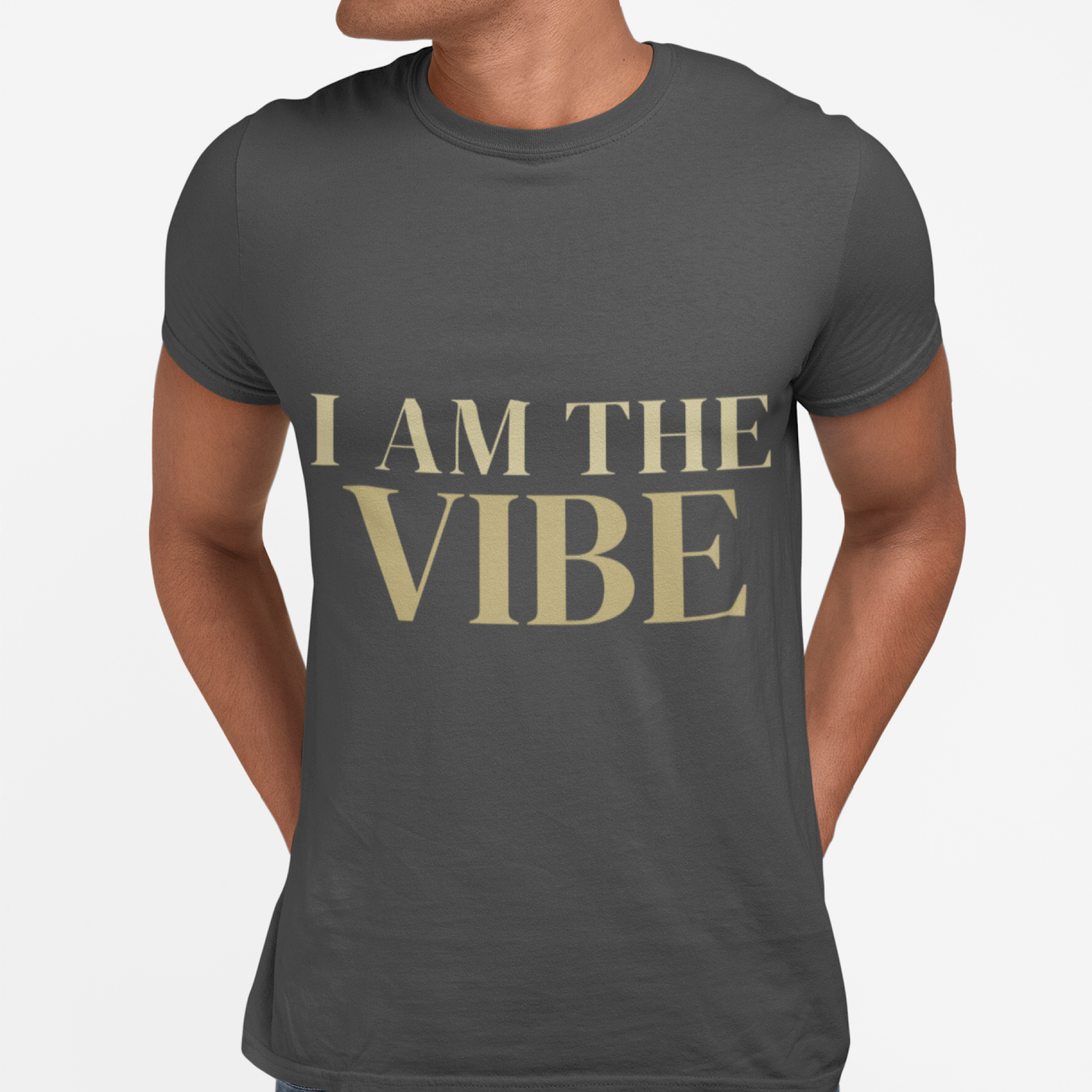 Person wearing a dark gray t-shirt with 'I AM THE VIBE' text in gold on a light gray background