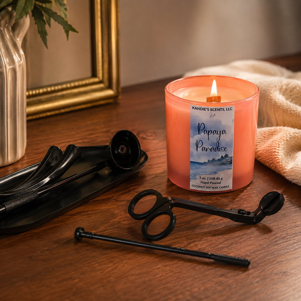 Candle labeled 'Paradise' on a wooden surface with scissors and other items.