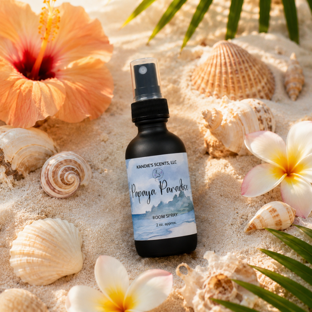 Room spray bottle labeled 'Papaya Paradise' on sand with flowers and shells