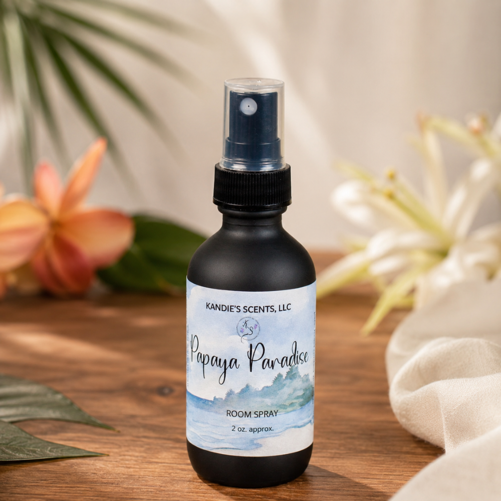 Room spray bottle labeled 'Papaya Paradise' by Kandie's Scents on a wooden surface with plants in the background.