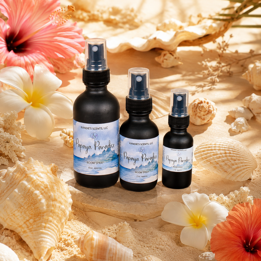 Three bottles of 'Papaya Paradise' room spray with floral and shell decorations on a sandy background.