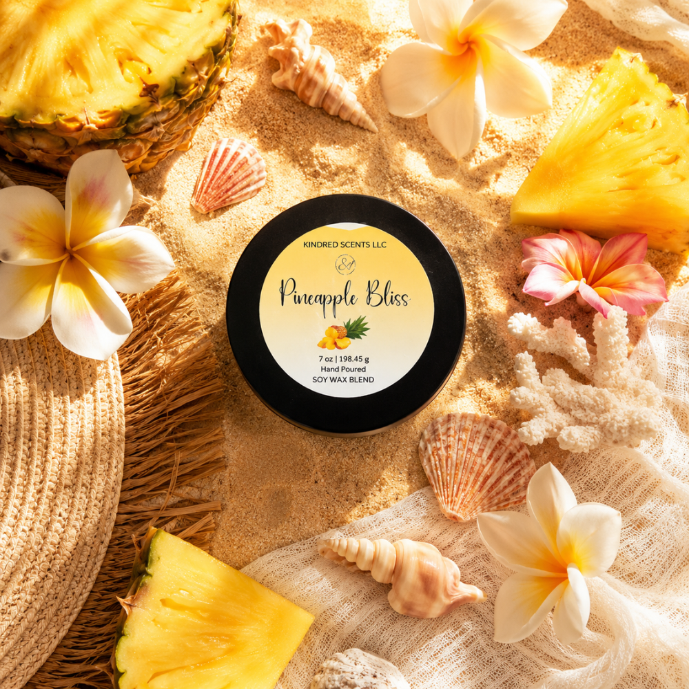 Pineapple Bliss candle surrounded by pineapple slices, flowers, and shells on sand.