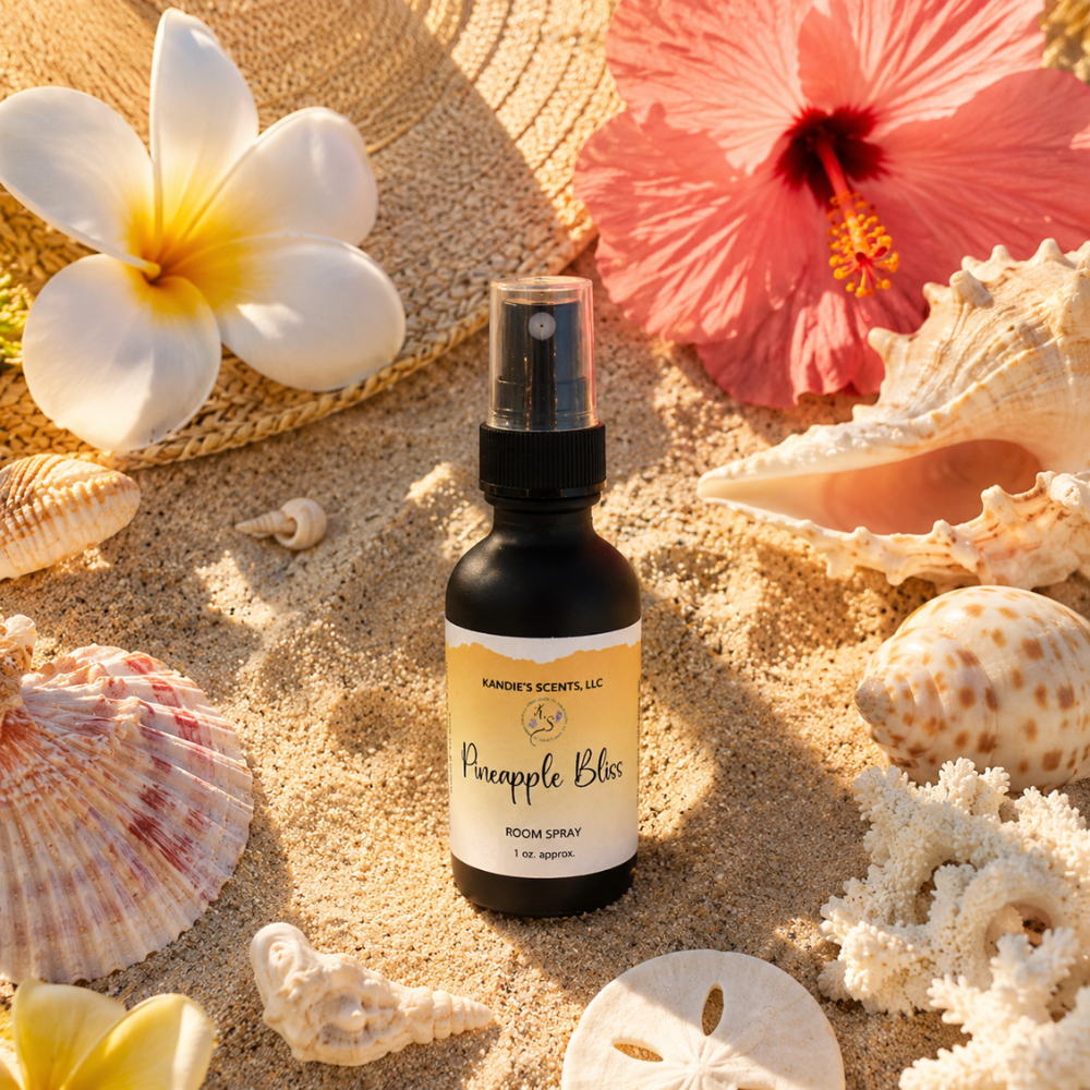 Room spray bottle labeled 'Pineapple Bliss' surrounded by seashells and flowers on sand