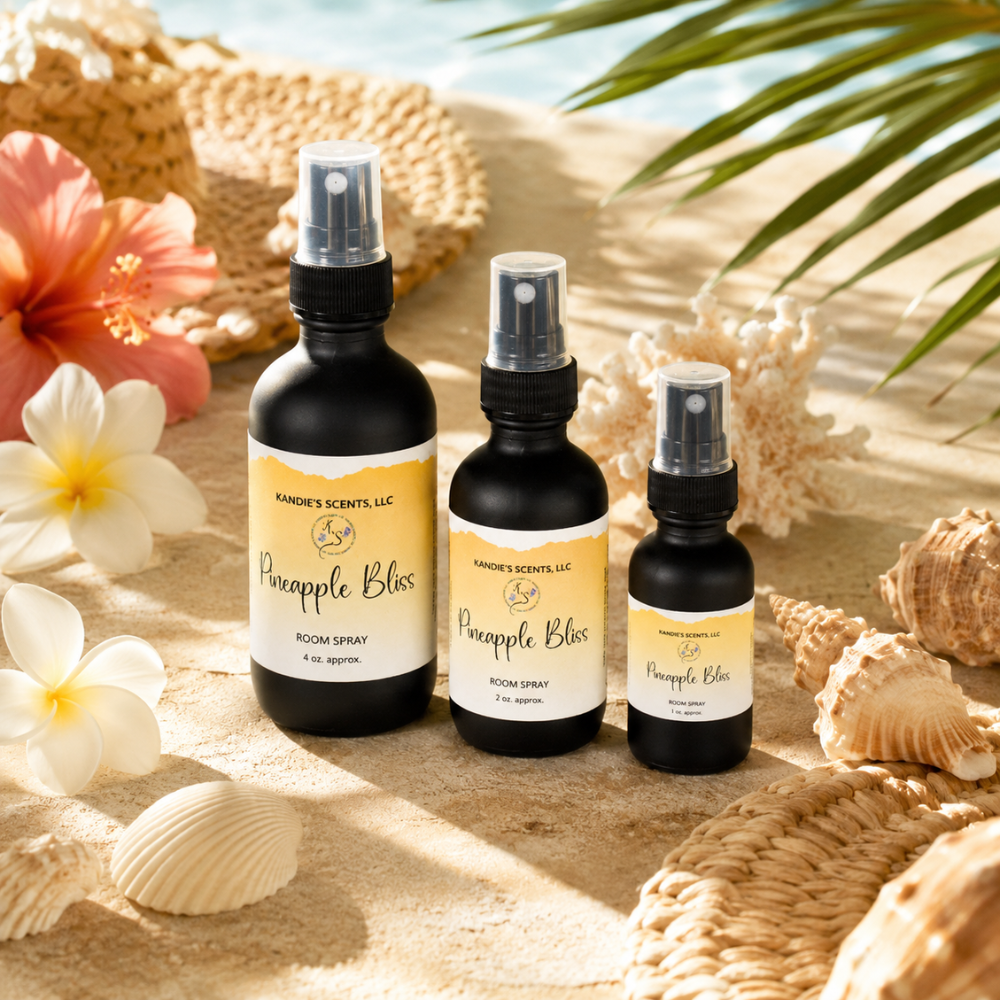 Three bottles of 'Pineapple Bliss' room spray by Kandie's Scents on a sandy background with flowers and shells.