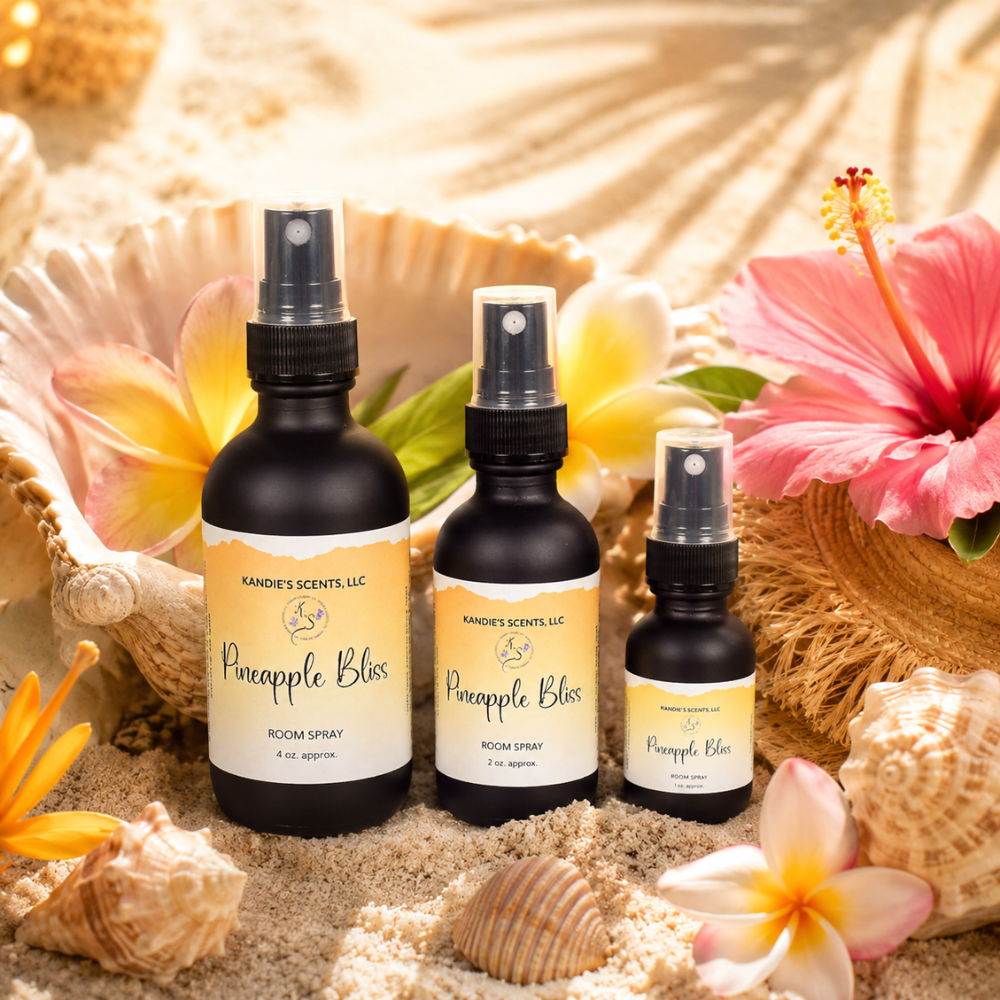 Three 'Pineapple Bliss' room spray bottles with seashells and flowers on a sandy background.
