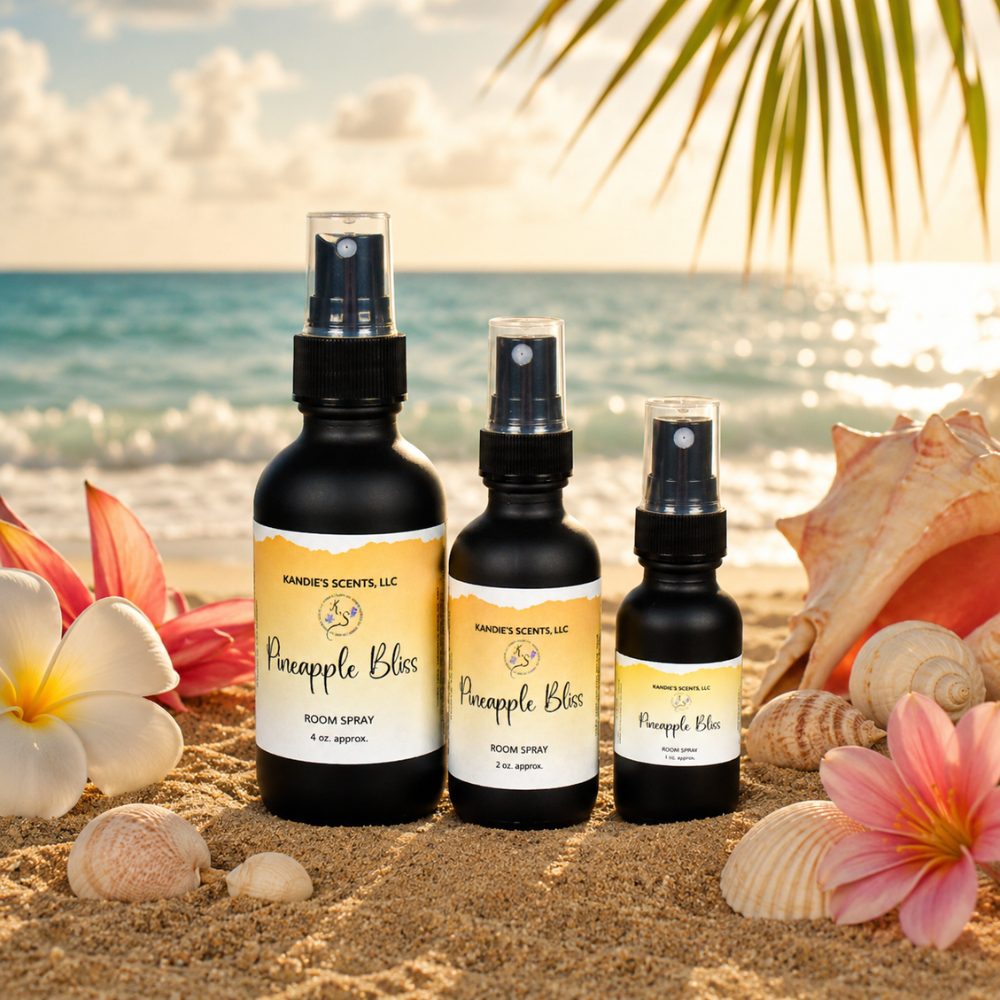 Three bottles of Pineapple Bliss room spray on a sandy beach with flowers and shells.