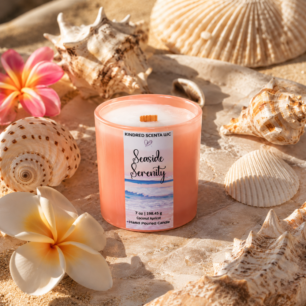 Candle labeled 'Seaside Serenity' surrounded by seashells and flowers on sand
