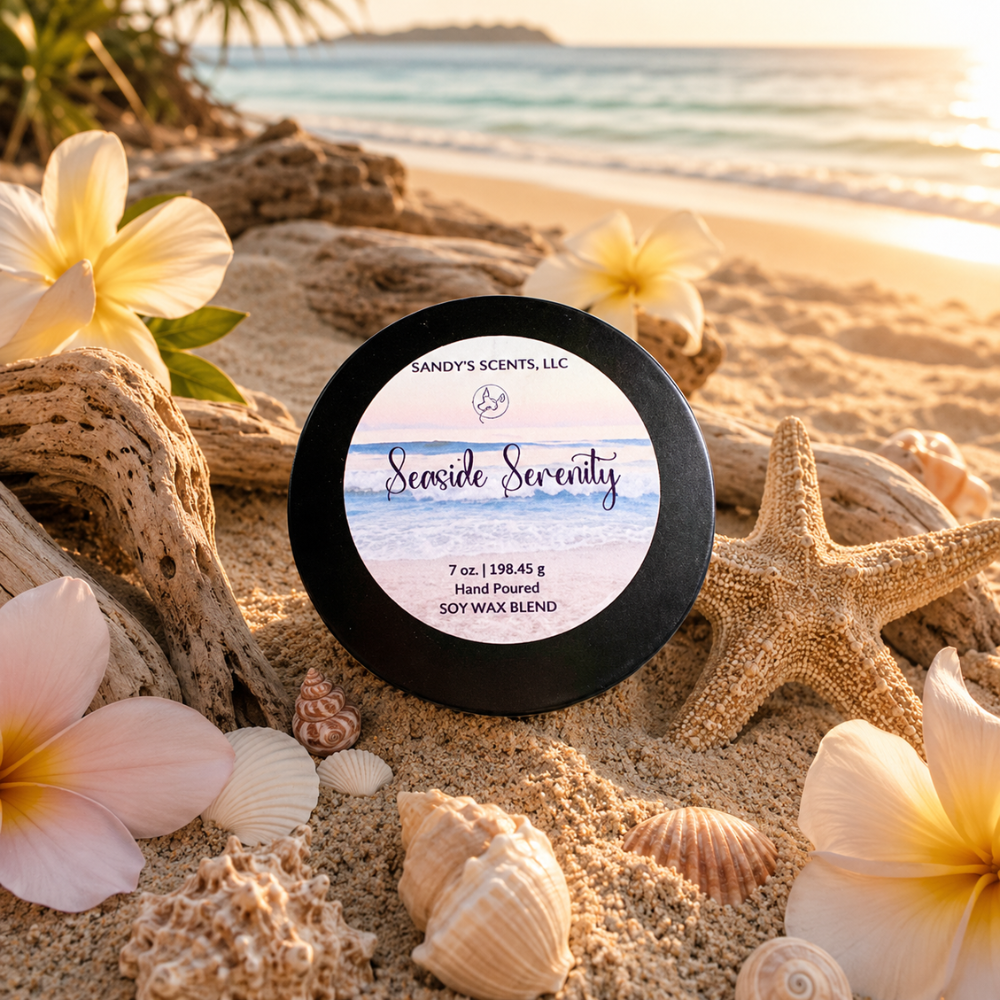Scented candle labeled 'Seaside Serenity' on a sandy beach with flowers and shells.