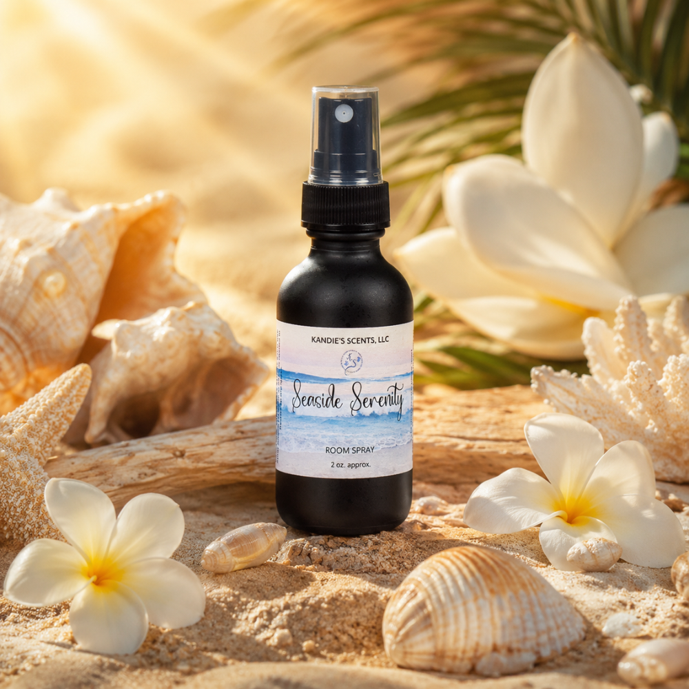 Room spray bottle labeled 'Seaside Serenity' surrounded by seashells and flowers on sand