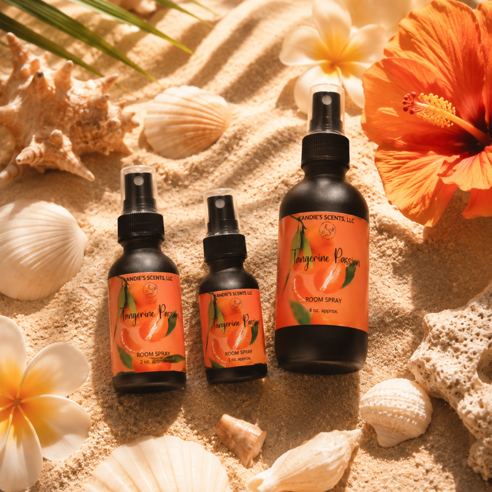 Three bottles of Tangerine Passion room spray on sand with seashells and flowers