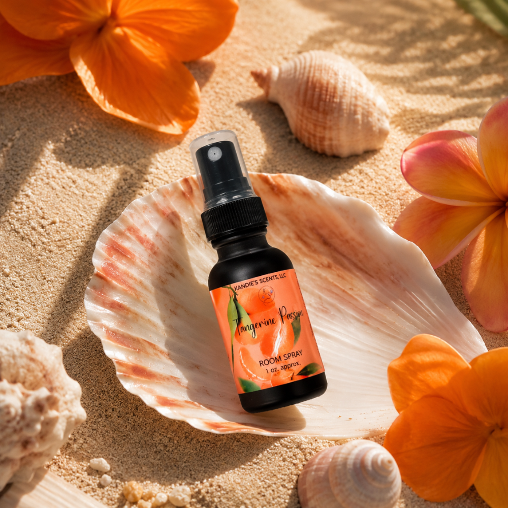 Room spray bottle with orange label on a shell surrounded by orange flowers and seashells on sand
