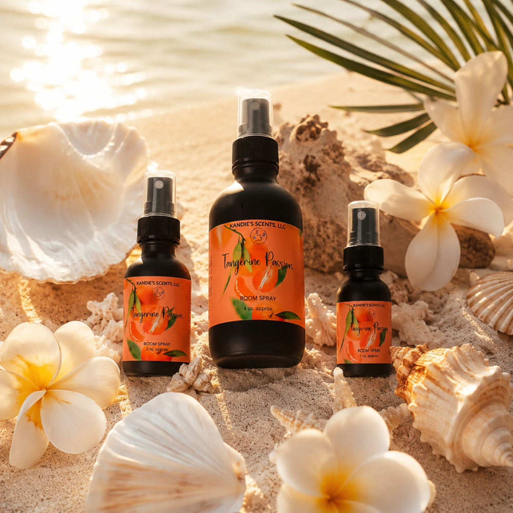 Three bottles of Tangerine Passion room spray on a sandy surface with flowers and shells.